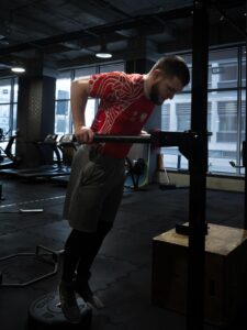 Mężczyzna w koszulce sportowej Polska trenuje uginanie łokci na drążku na siłowni