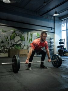 Niska pozycja startowa mężczyzny przygotowującego się do podniesienia sztangi (martwy ciąg) z zielonymi obciążeniami Eleiko. Nowoczesna siłownia. Fotografia treningu siłowego