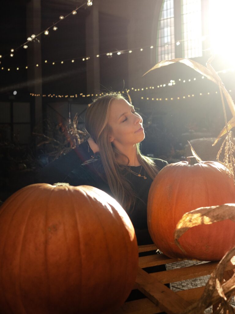 piękna blond dziewczyna w jesiennej scenerii z dyniami i światłem słońca - sesja portretowa Łódź